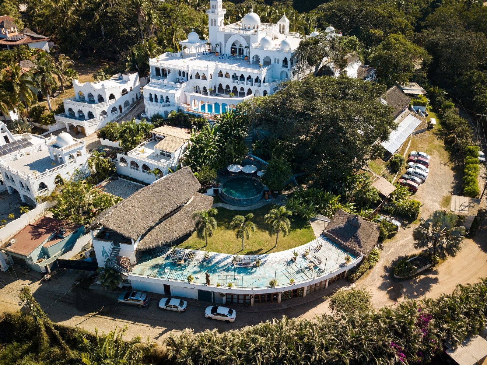 Vista aérea de Mamica San Pancho: casas blancas, palapas y alberca rodeadas de palmeras