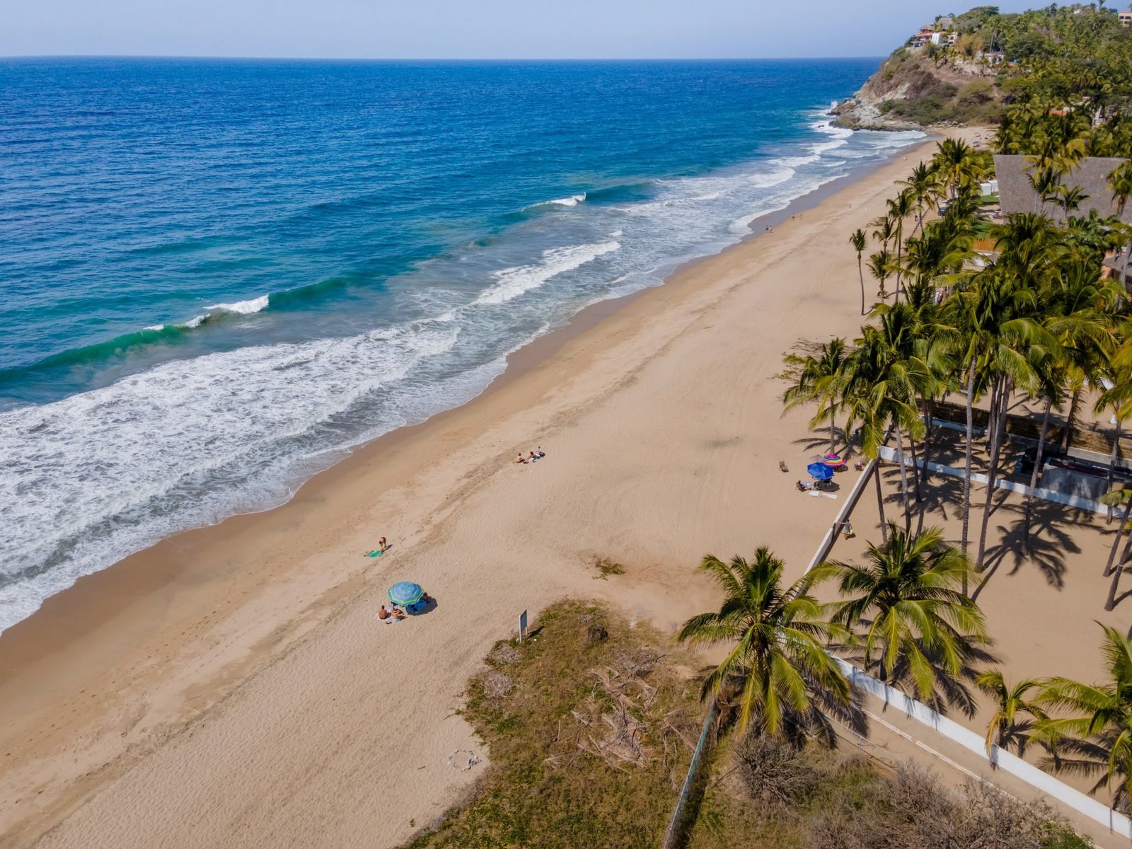 Vista aérea de la playa larga de Bucerías con palmeras y sombrillas sobre la arena