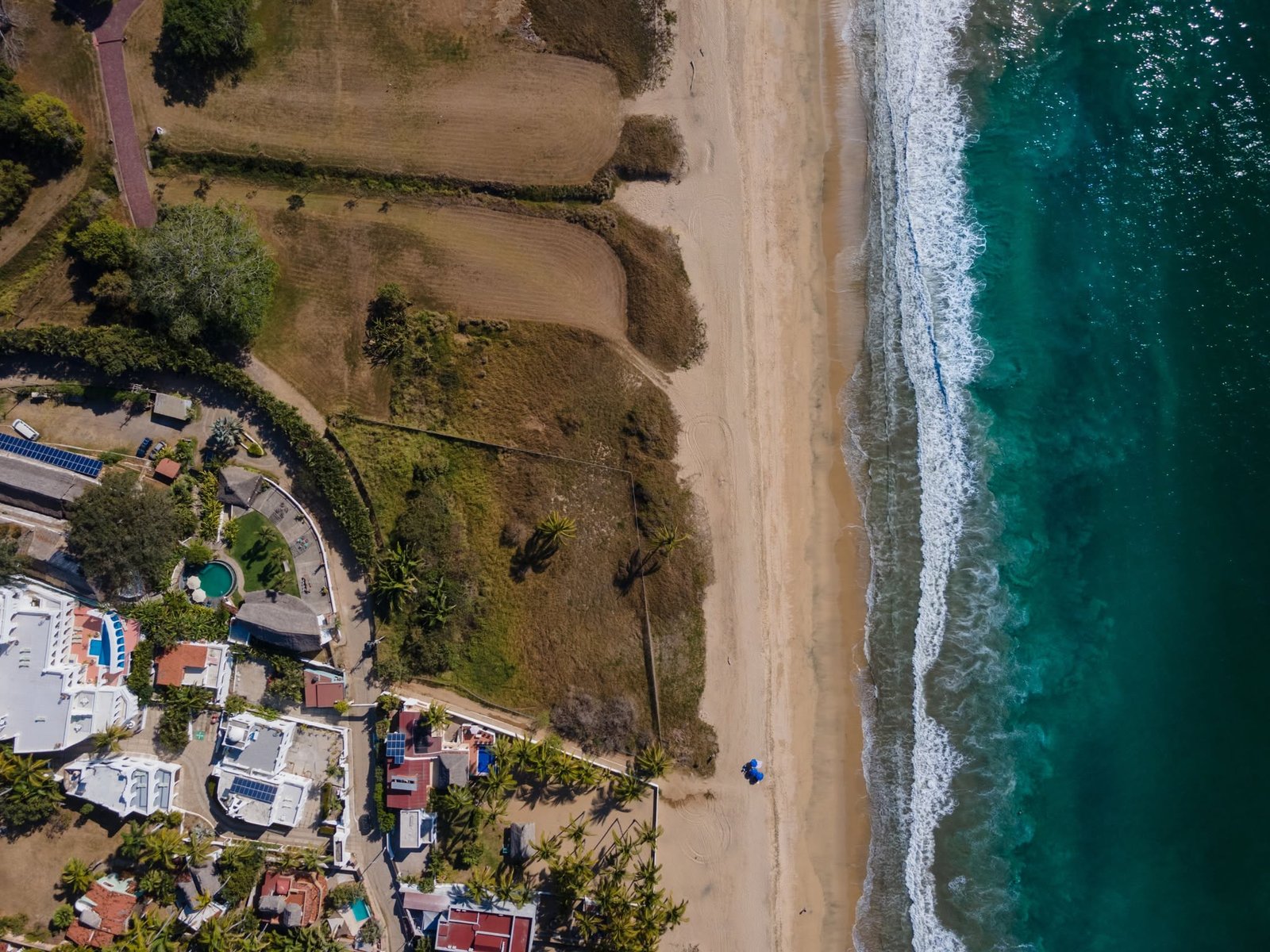 Vista aérea de la costa de Riviera Nayarit con la playa larga y el pueblo entre palmeras