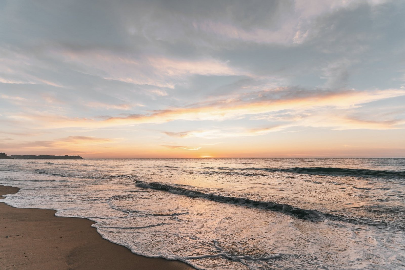 Atardecer sobre el Pacífico con la ola rompiendo en la orilla en Riviera Nayarit