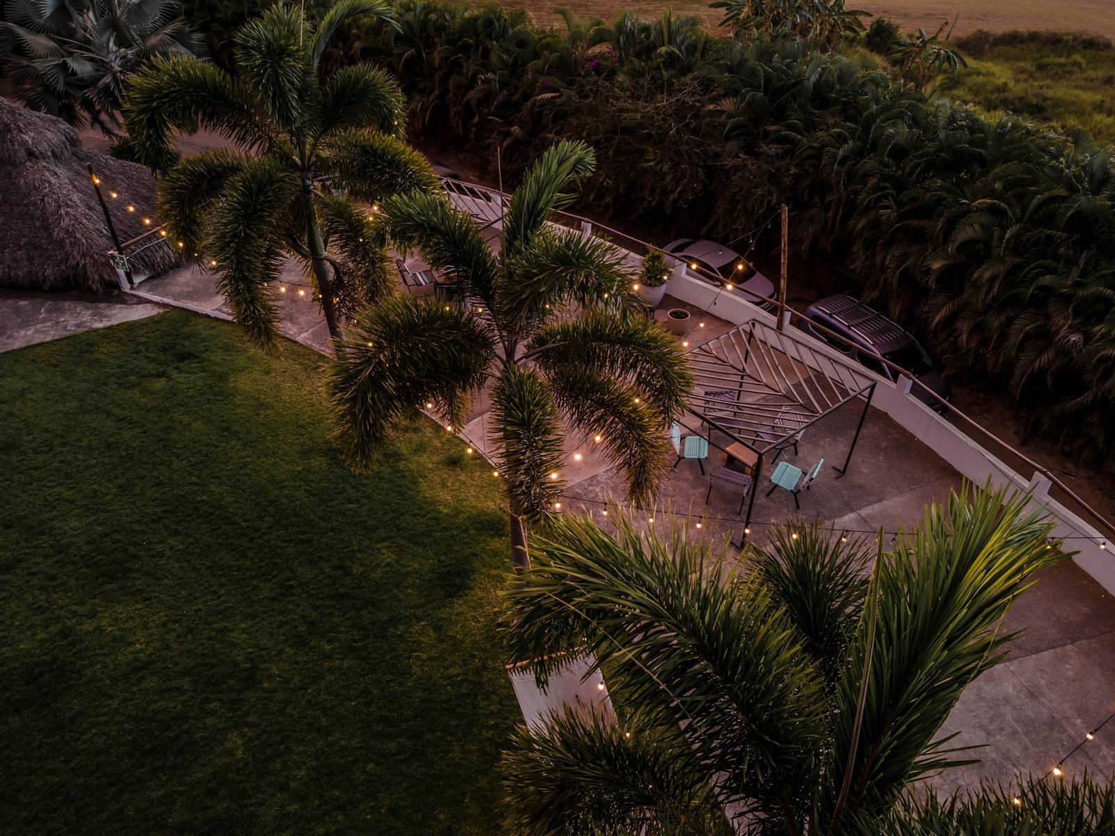 Mesa larga puesta con velas y luces colgantes en el jardín de noche