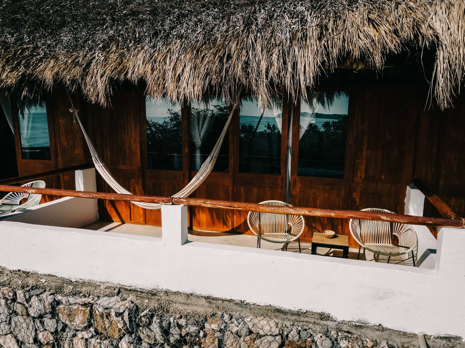 Terraza con hamaca bajo techo de palapa y vista al mar en Mamica La Cruz