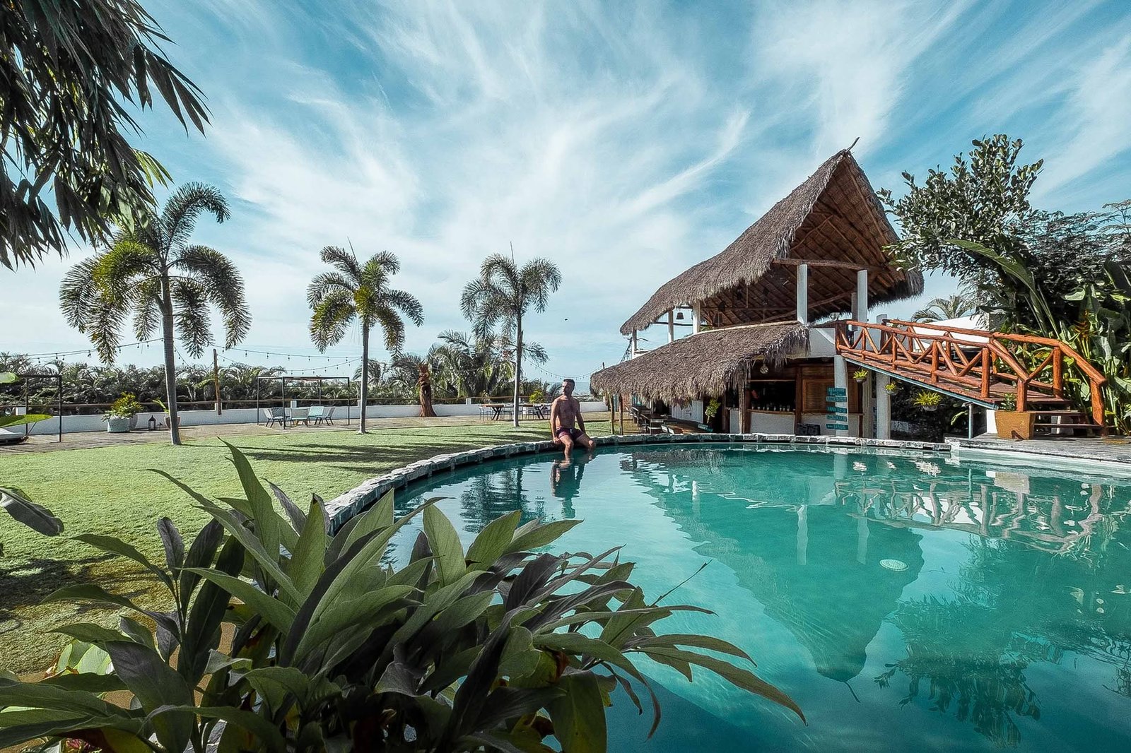 Alberca del hotel con palapa alta y palmeras, lista para recibir a un grupo
