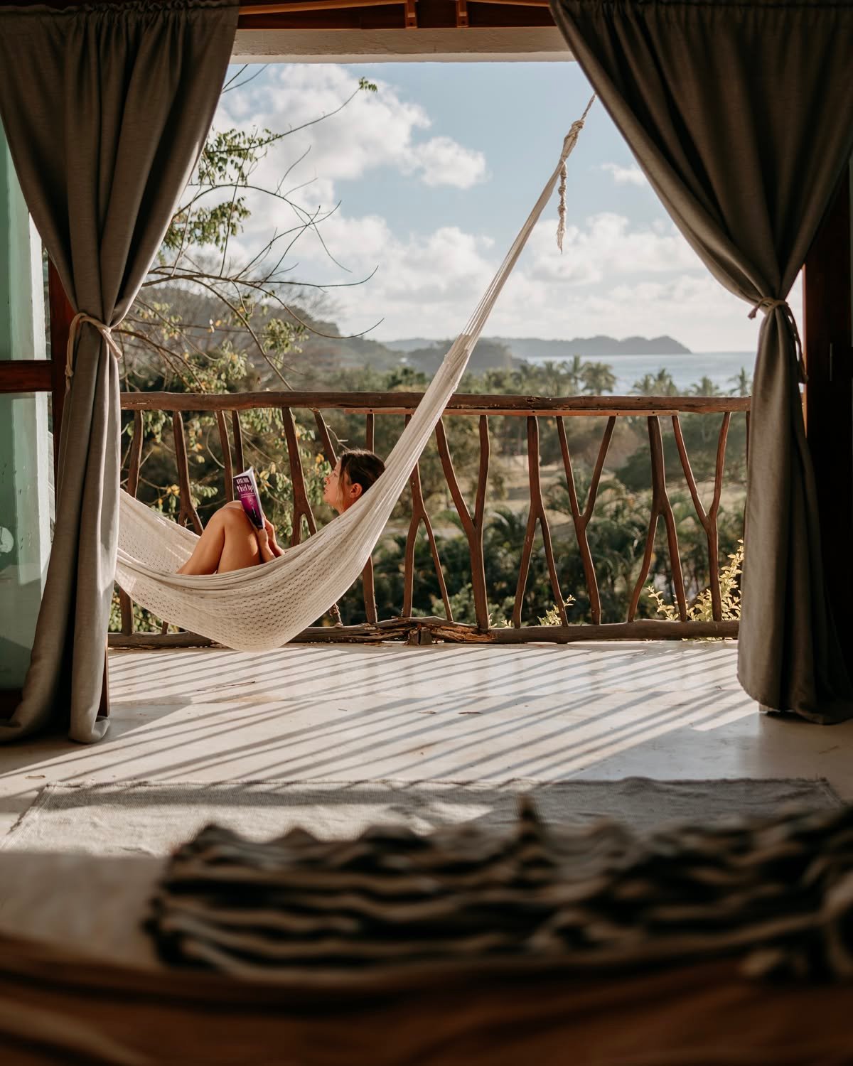 Terraza de una suite con hamaca colgada entre cortinas y vista a la sierra