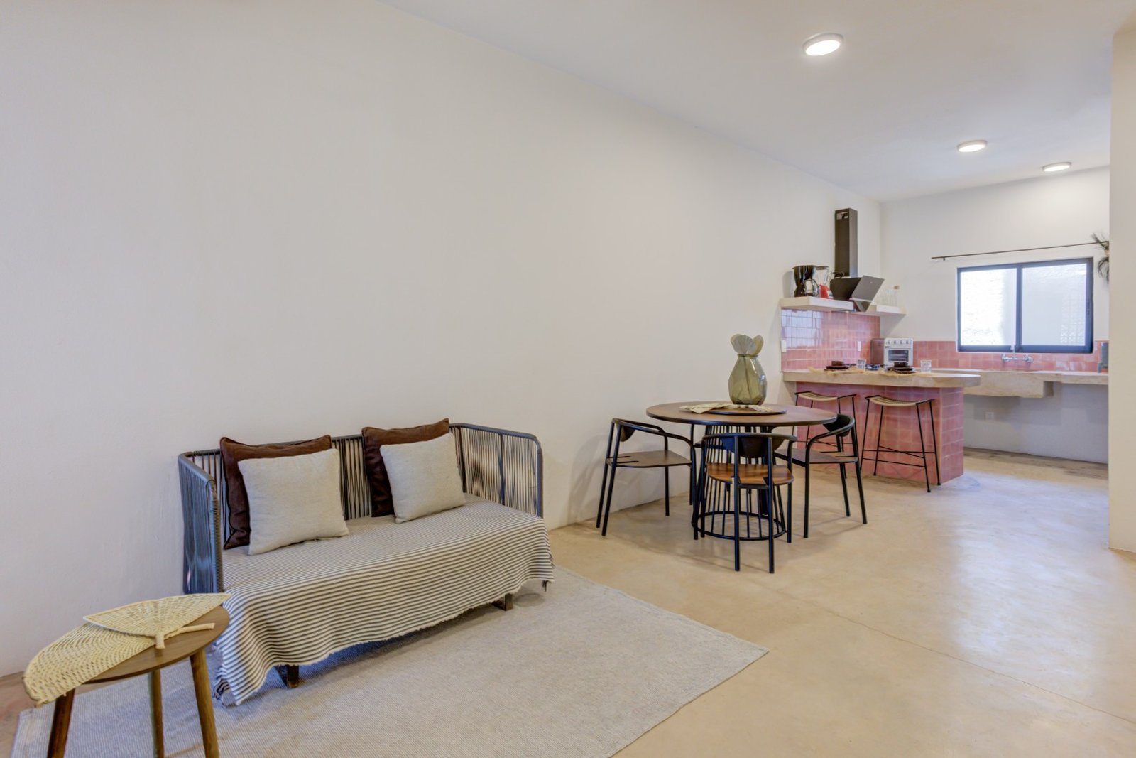 Sala de Heliconia con sofá cama, comedor y cocina al fondo