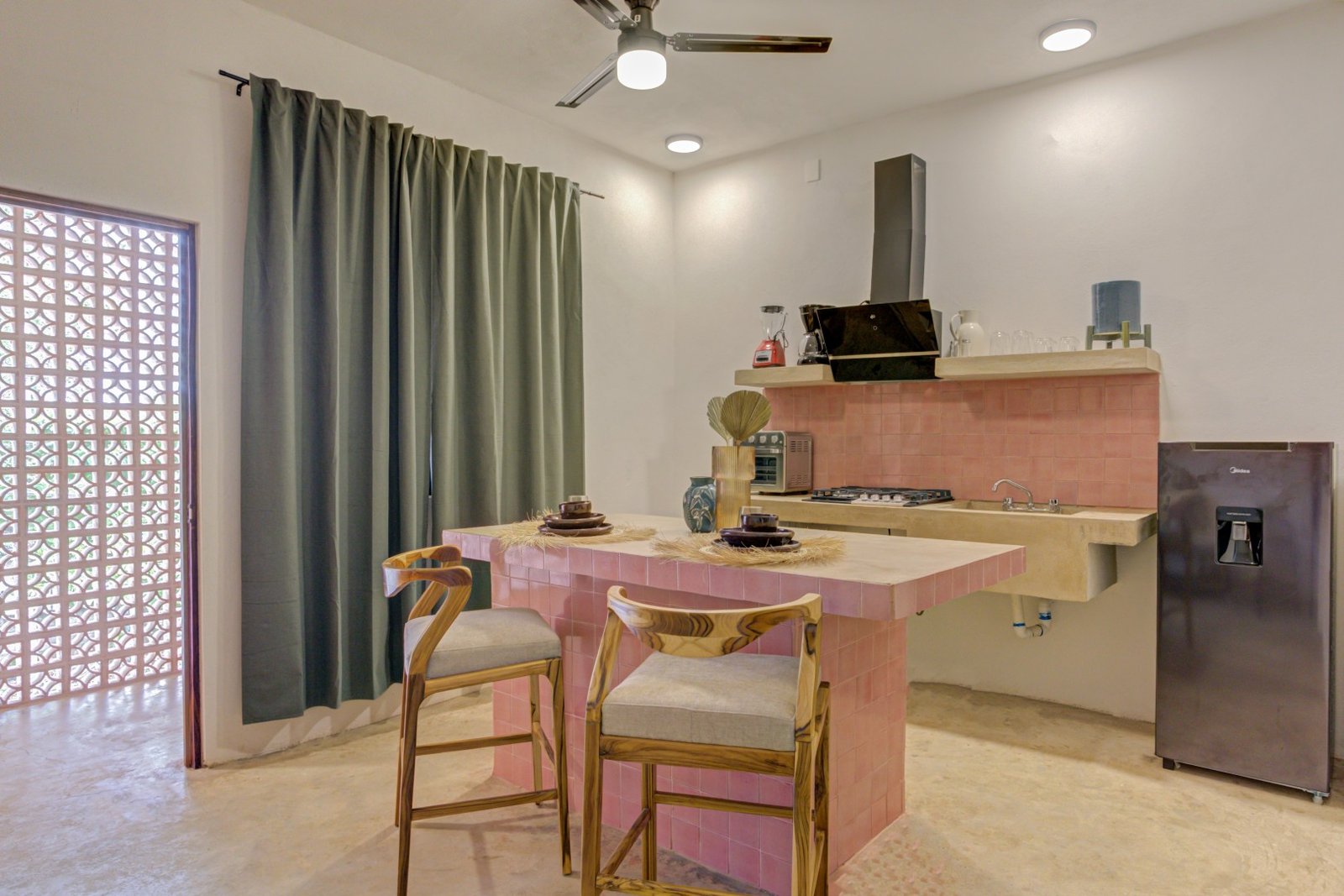 Cocina de talavera rosa con barra, bancos y ventana de celosía en Mamica La Cruz