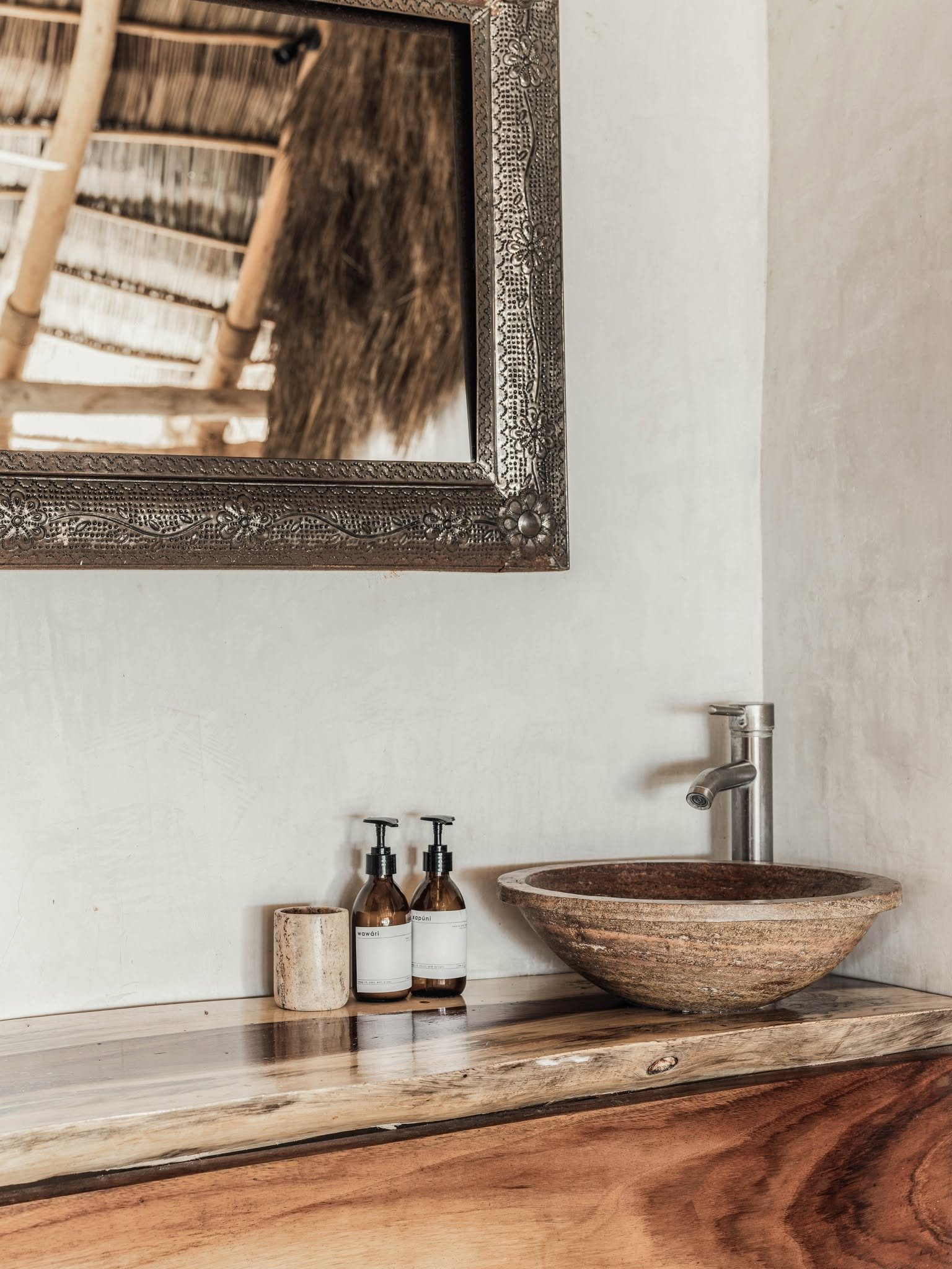 Lavabo de barro sobre repisa de madera con amenidades locales