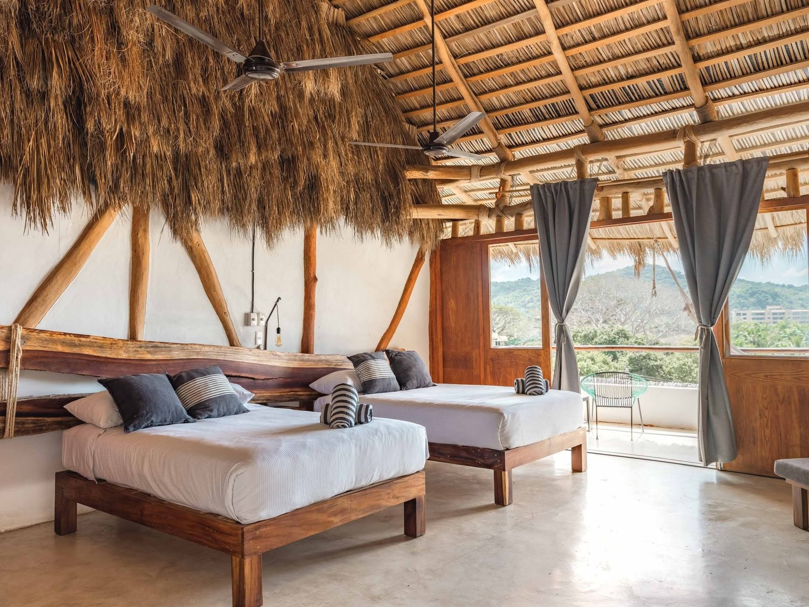 Suite Doble Sierra con vigas de madera y cortinas abiertas a la terraza