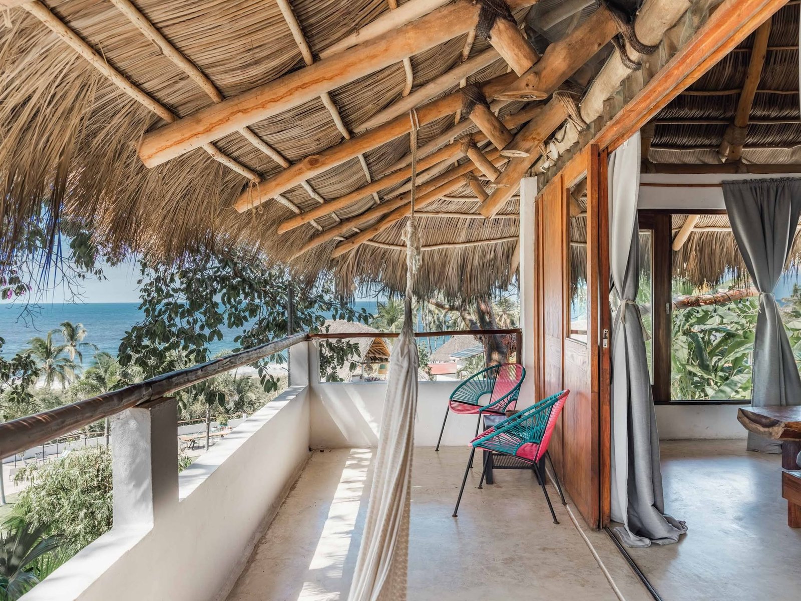 Terraza privada con hamaca, sillas Acapulco y vista al mar bajo techo de palapa
